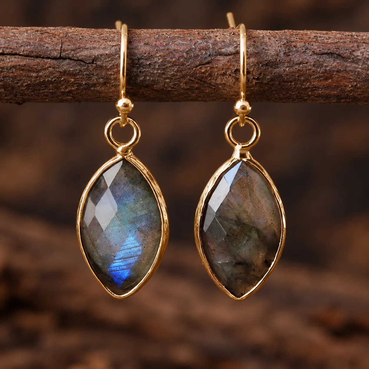 Les Feuilles du Druide, paire de boucles d’oreilles en labradorite, forme de feuille et montures dorées sur une branche